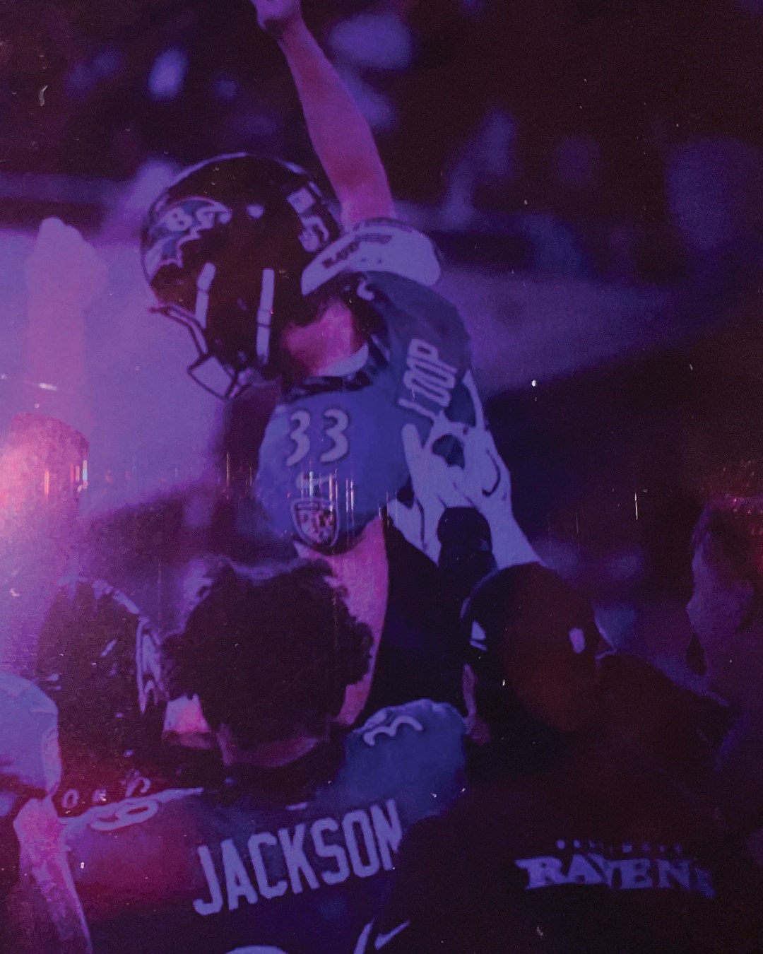 The kicker lifted into the air by teammates after the kick, helmet in one raised hand, a Jackson jersey in the foreground.